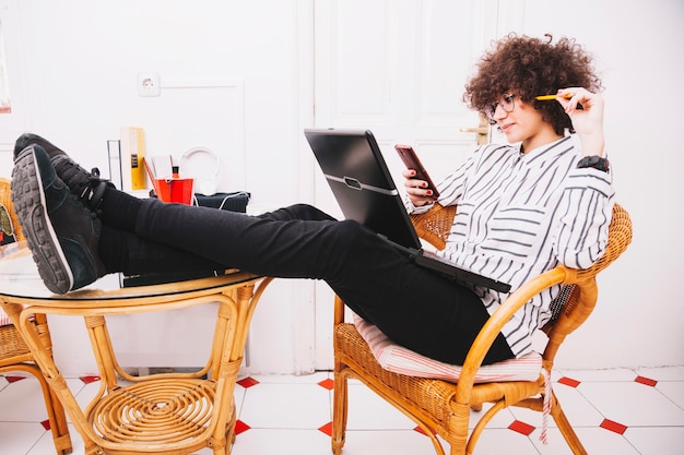 Foto gratuita adolescente con laptop usando teléfono inteligente