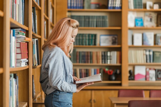 Adolescente leyendo cerca de estanterías