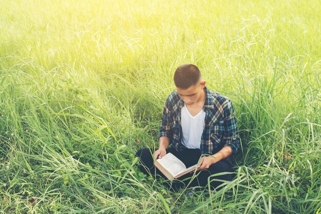 Adolescente leyendo un libro sentado en el césped