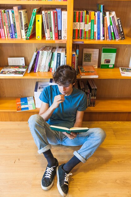 Adolescente leyendo y sentado en el piso
