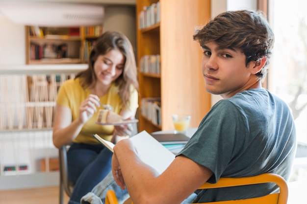 Adolescente con libro sentado cerca de la novia