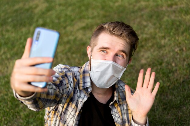 Adolescente con mascarilla tomando un selfie