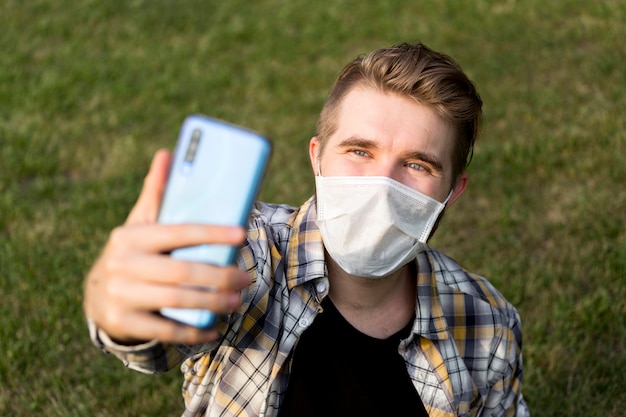 Foto gratuita adolescente con mascarilla tomando un selfie