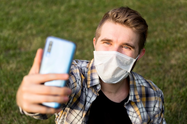 Adolescente con mascarilla tomando un selfie