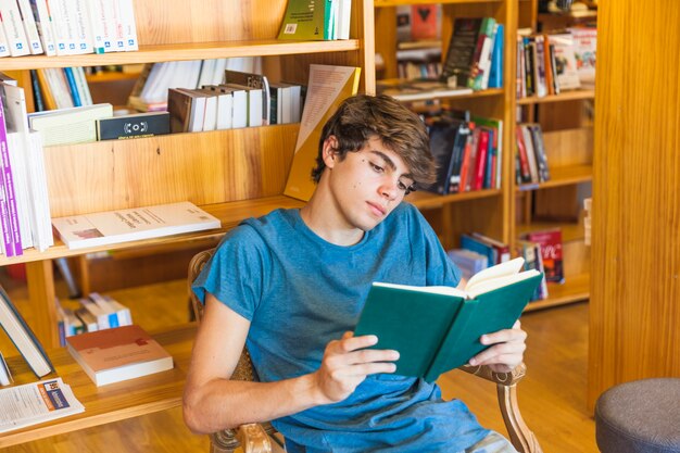 Adolescente masculino leyendo en silla