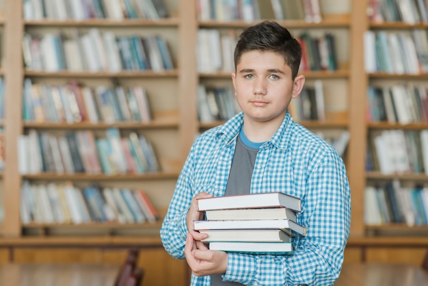 Adolescente masculino con pila de libros