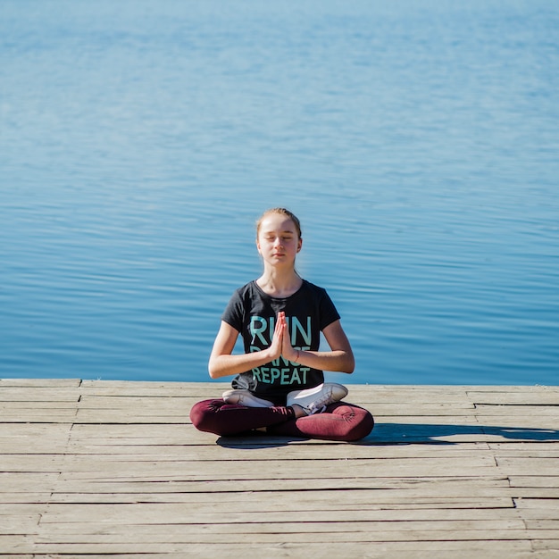 Foto gratuita adolescente meditando cerca del agua