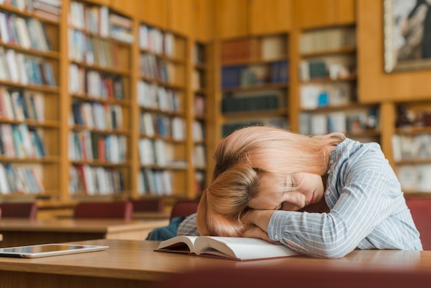 Adolescente mujer durmiendo en la biblioteca