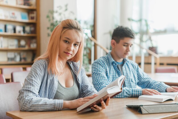 Adolescente mujer con libro cerca de amigo