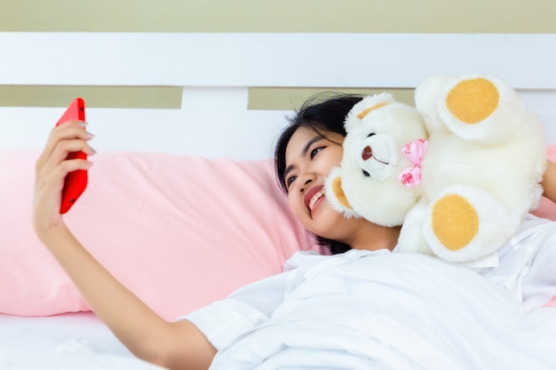 Adolescente mujer uso smartphone chateando en la cama