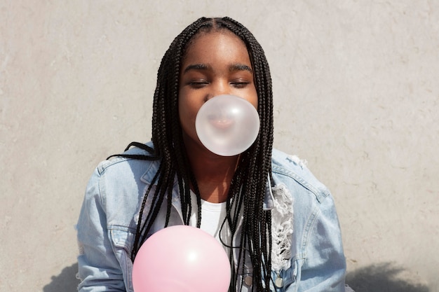 Adolescente negra jugando haciendo una burbuja de chicle
