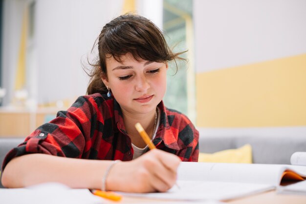 Adolescente niña escribiendo en el libro de texto