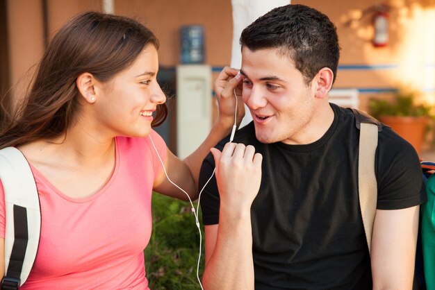 Adolescente y niña escuchando música juntos y coqueteando en la escuela