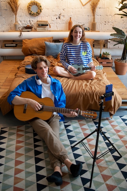 Adolescente y niña grabando música en su estudio casero con guitarra