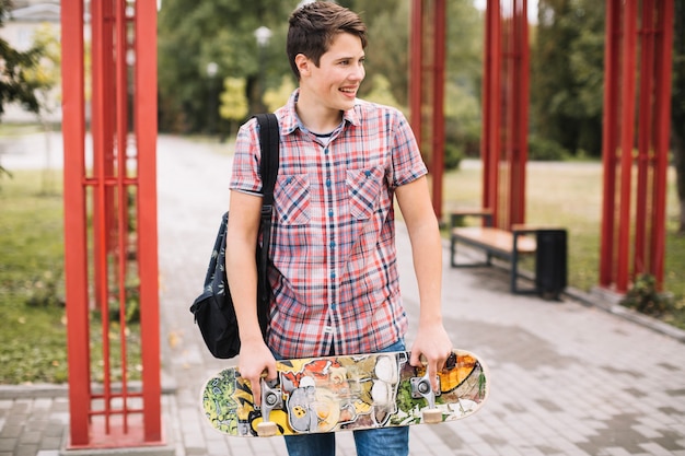 Foto gratuita adolescente con patineta cerca de pilares de metal