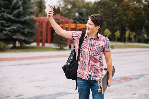 Adolescente con patineta tomando selfie