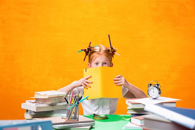 La adolescente pelirroja con gran cantidad de libros en casa. Tiro del estudio