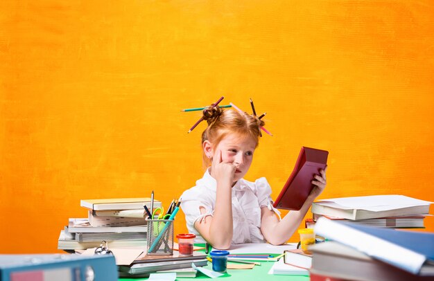 La adolescente pelirroja con muchos libros en casa.