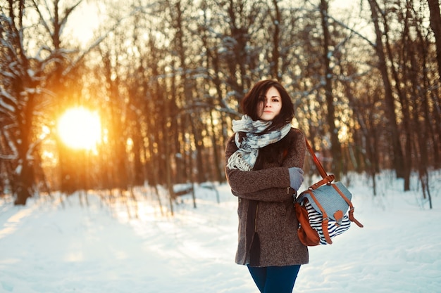 Adolescente de pie con su bolso en un bosque nevado
