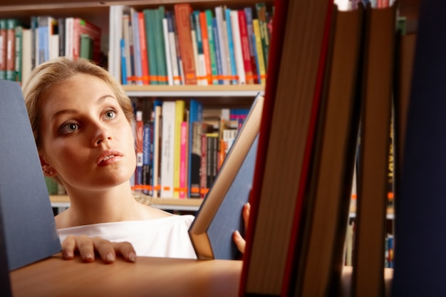 Adolescente poniendo un libro en la estantería