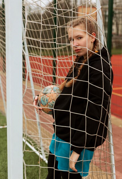 Adolescente posando con una pelota al aire libre