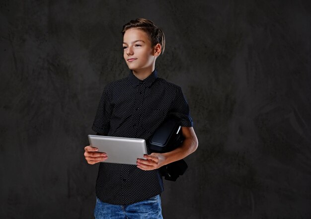 El adolescente positivo tiene tablet PC sobre fondo gris.