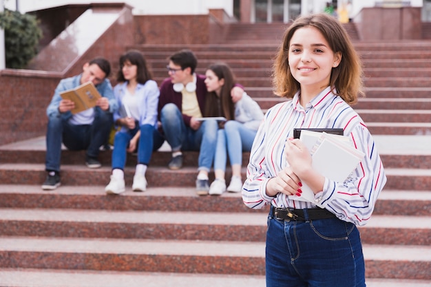 Foto gratuita adolescente que coloca y que sostiene el cuaderno en manos