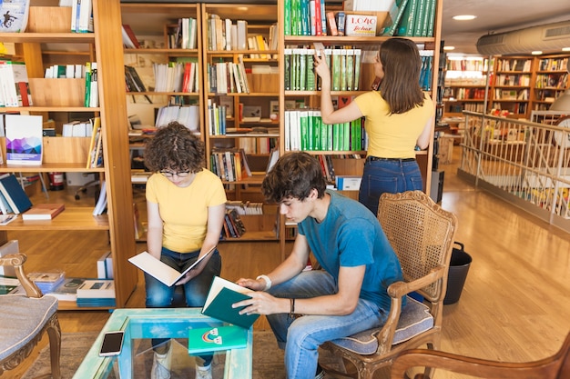 Adolescente que elige el libro cerca de amigos de lectura