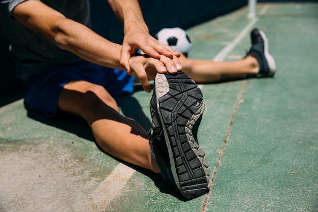 Adolescente que estira el pie en el campo de fútbol