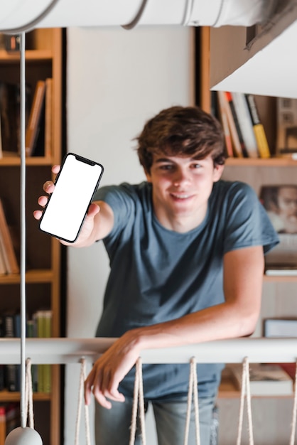 Adolescente que muestra el teléfono inteligente en la biblioteca