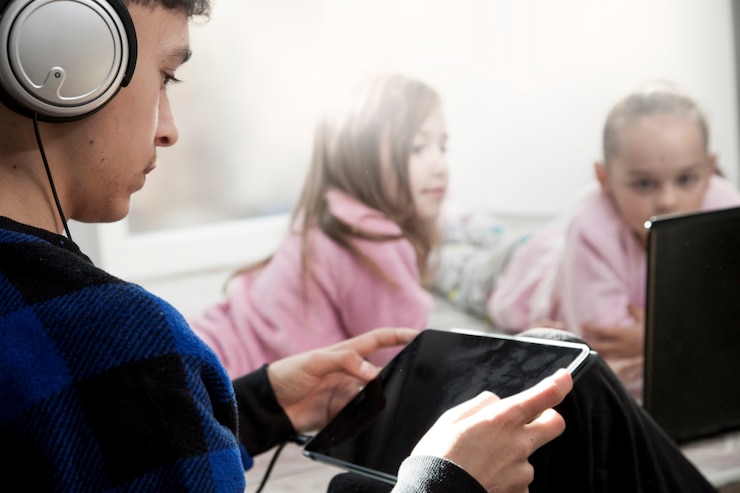 Foto gratuito adolescente que usa la tableta cerca de muchachas con la computadora portátil