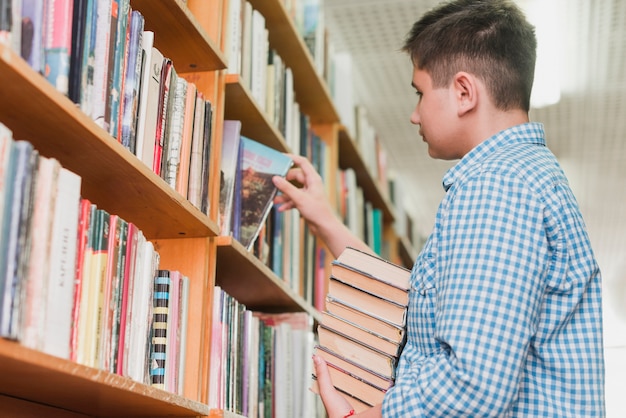 Adolescente recogiendo libros del estante