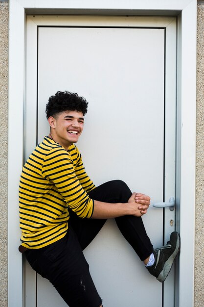 Adolescente riendo en camisa brillante de pie en la puerta