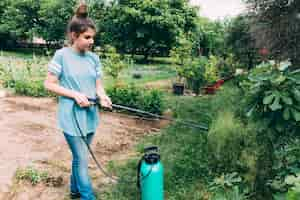 Foto gratuita adolescente rociando plantas en el jardín