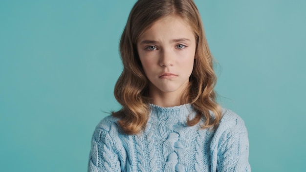 Foto gratuita una adolescente rubia molesta que se siente triste por las malas notas en la escuela posando aislada de fondo azul. niña ofendida