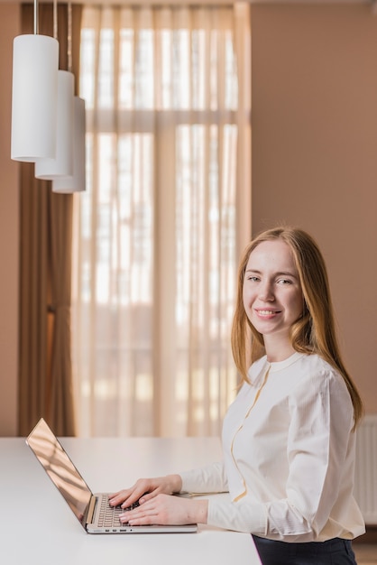 Foto gratuita adolescente rubia posando con su portátil