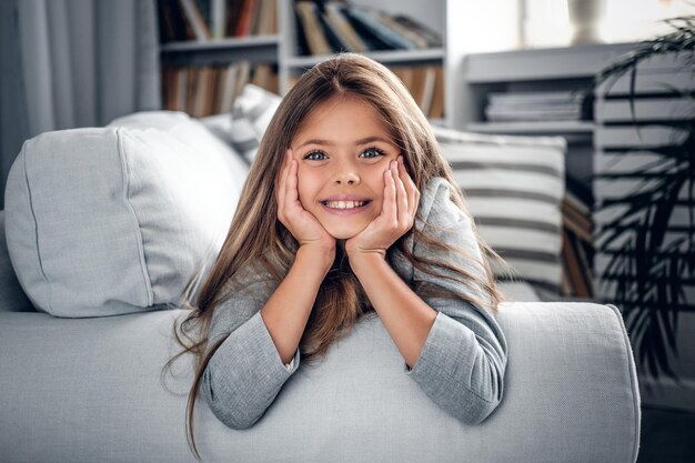 Adolescente rubia sonriente positiva acostada en un sofá.