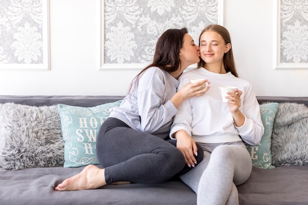 Adolescente rubia sosteniendo café mientras se besaba