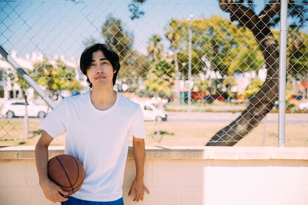 Adolescente serio con pelota en el campo.