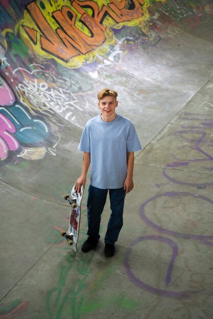 Adolescente sonriente de alto ángulo con patineta