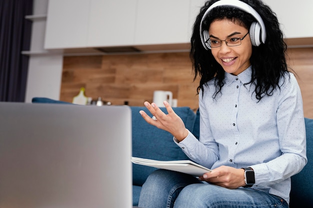 Adolescente sonriente con auriculares y portátil durante la escuela en línea