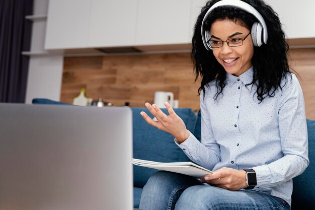 Adolescente sonriente con auriculares y portátil durante la escuela en línea