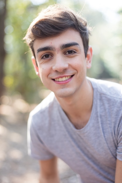 Adolescente sonriente con camiseta gris en el parque