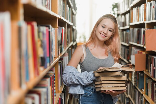 Adolescente sonriente con libros antiguos