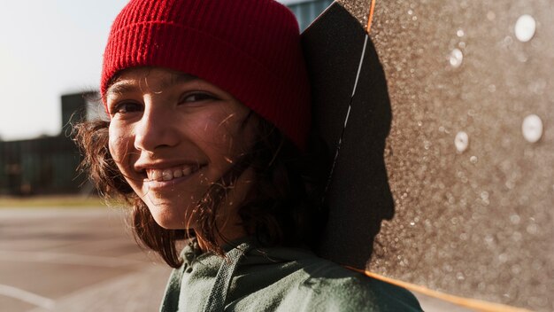 Adolescente sonriente con patineta en el parque