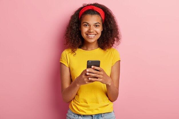 Adolescente sonriente con pelo rizado posando en camiseta amarilla