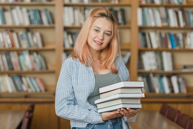 Adolescente sonriente con pila de libros