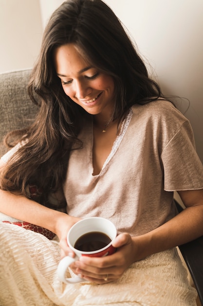 Adolescente sonriente que sostiene la taza de café disponible