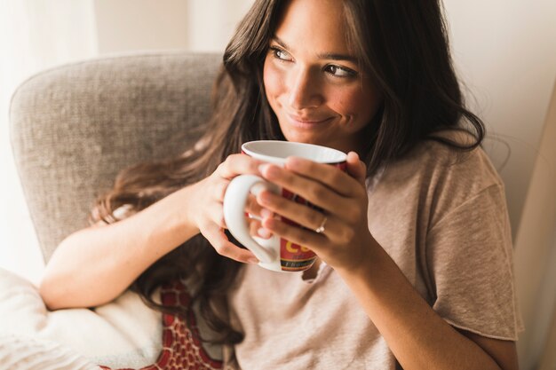 Adolescente sonriente que sostiene la taza de café