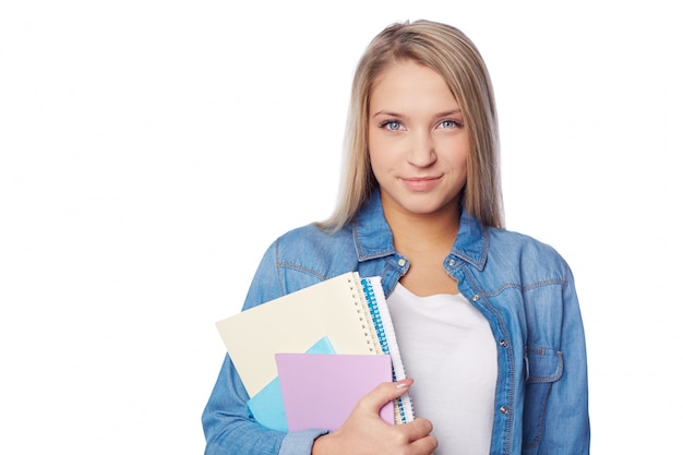 Adolescente sonriente sujetando sus cuadernos
